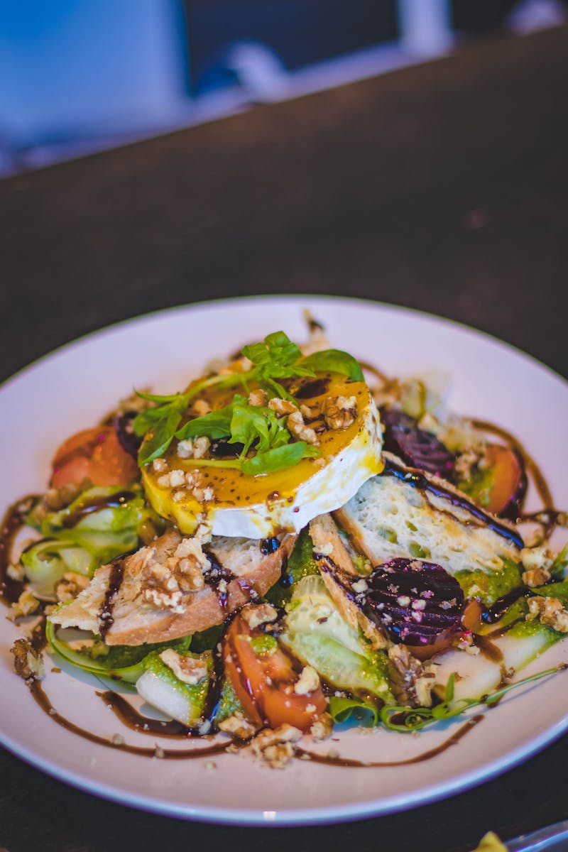 A vibrant gourmet salad with poached egg, fresh vegetables and nuts on a white plate.