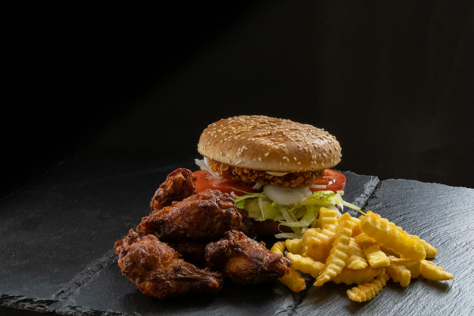 Tasty fast food meal featuring a crispy chicken burger, fries, and wings.