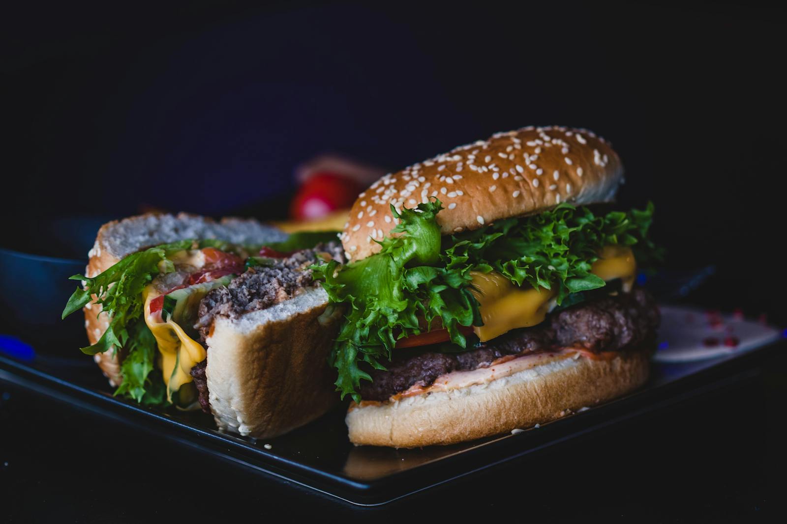 Delicious cheeseburger with lettuce and tomato served on a dark plate.