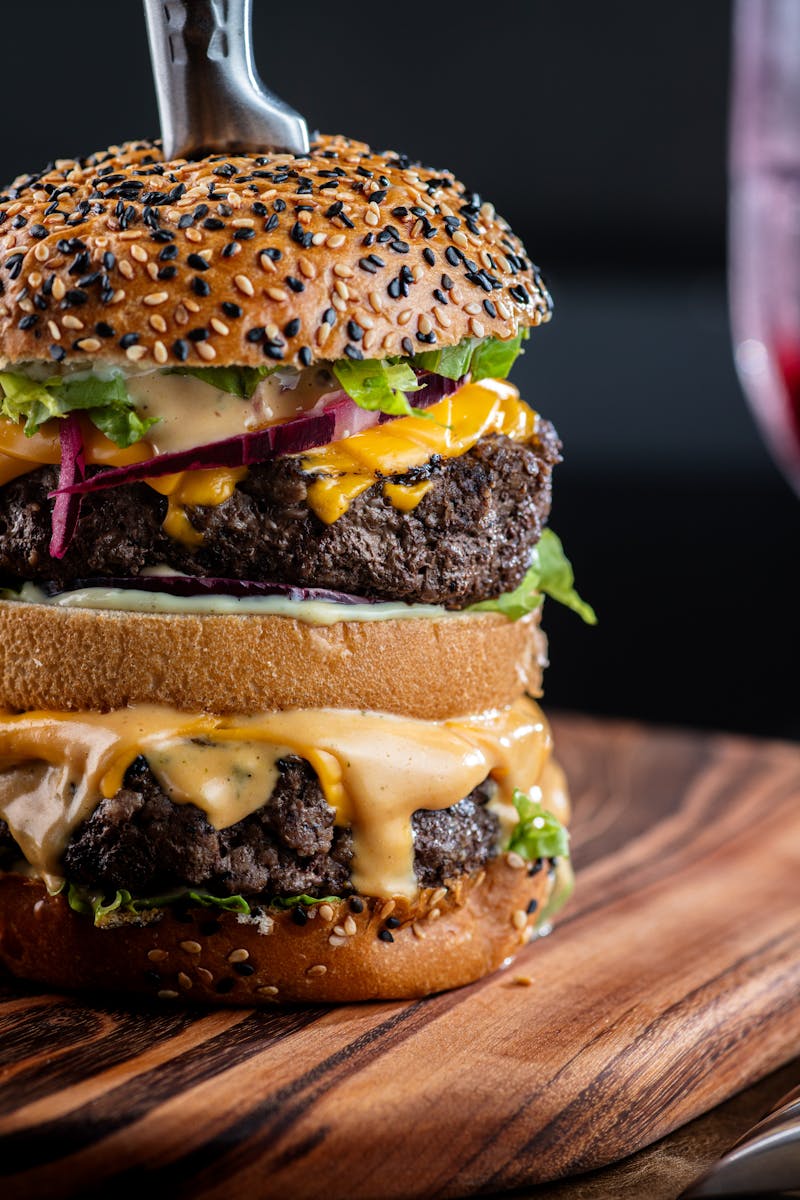 Close-up of a gourmet double cheeseburger with a sesame seed bun, perfect for food lovers.