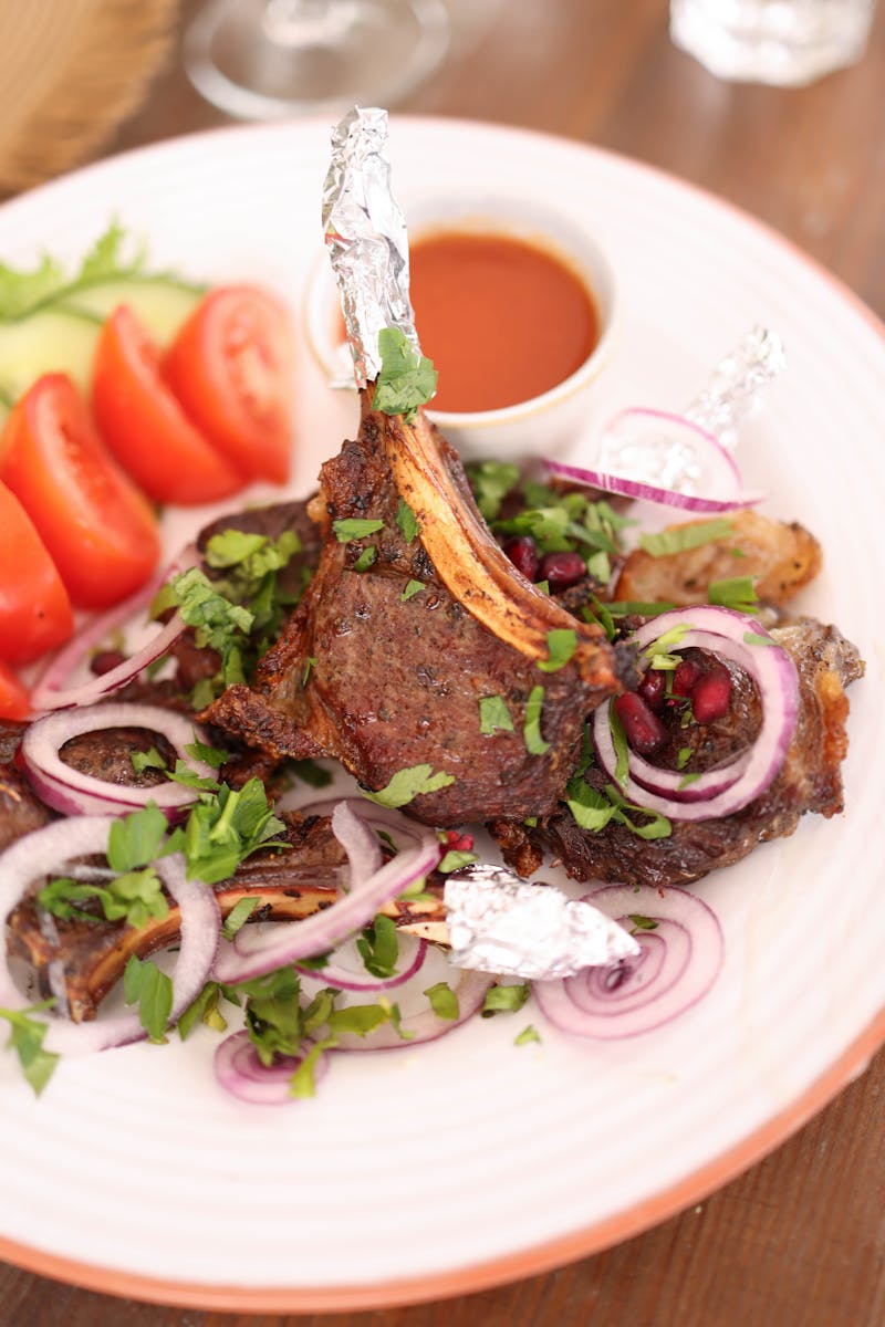 Savor the taste of grilled lamb chops served with fresh salad and dipping sauce.