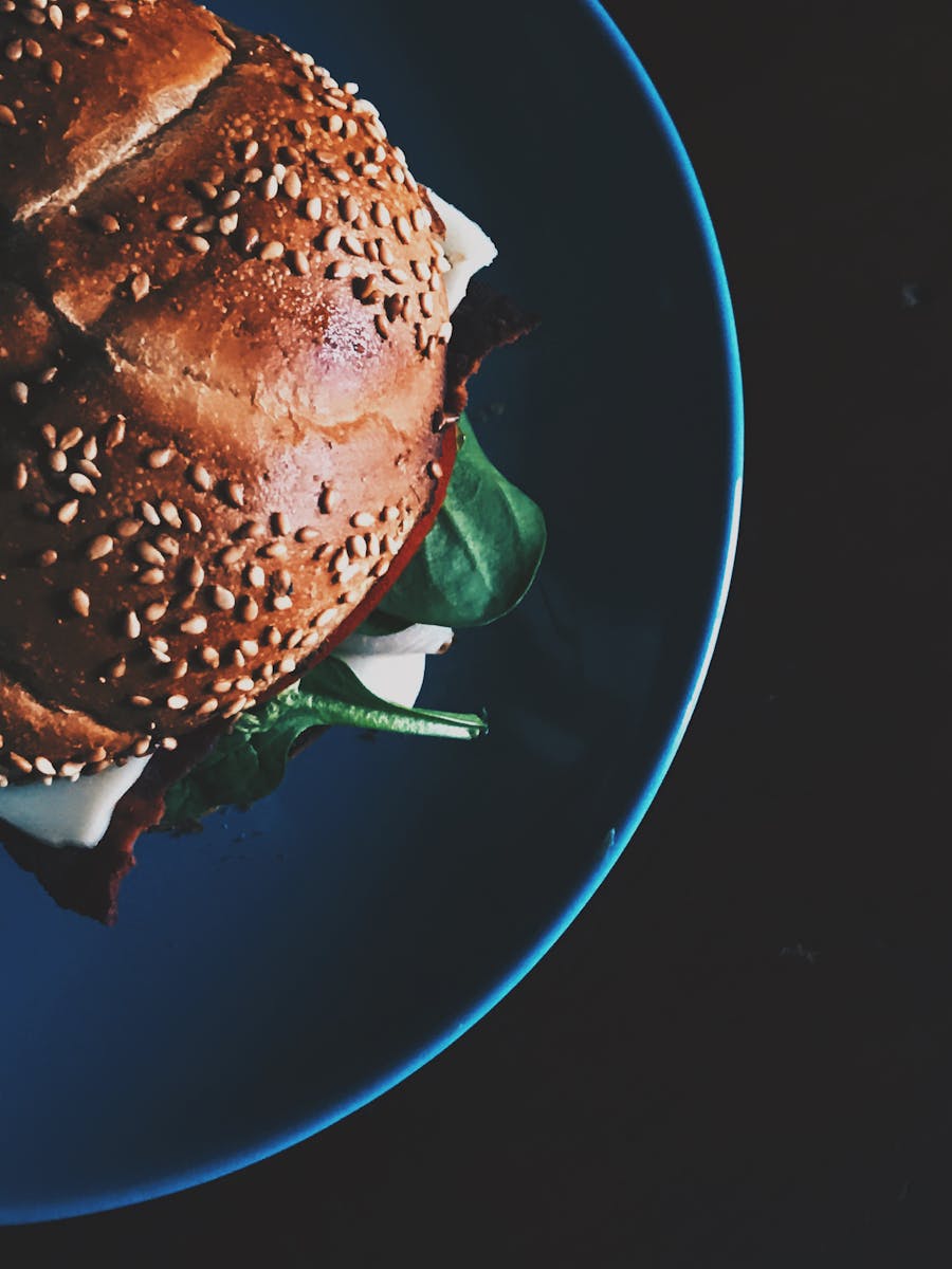 Delicious close-up of a gourmet sandwich with sesame seed bun and spinach on a plate.