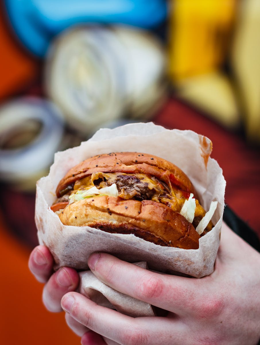 A mouth-watering cheeseburger held in hands, perfect for fast food lovers.