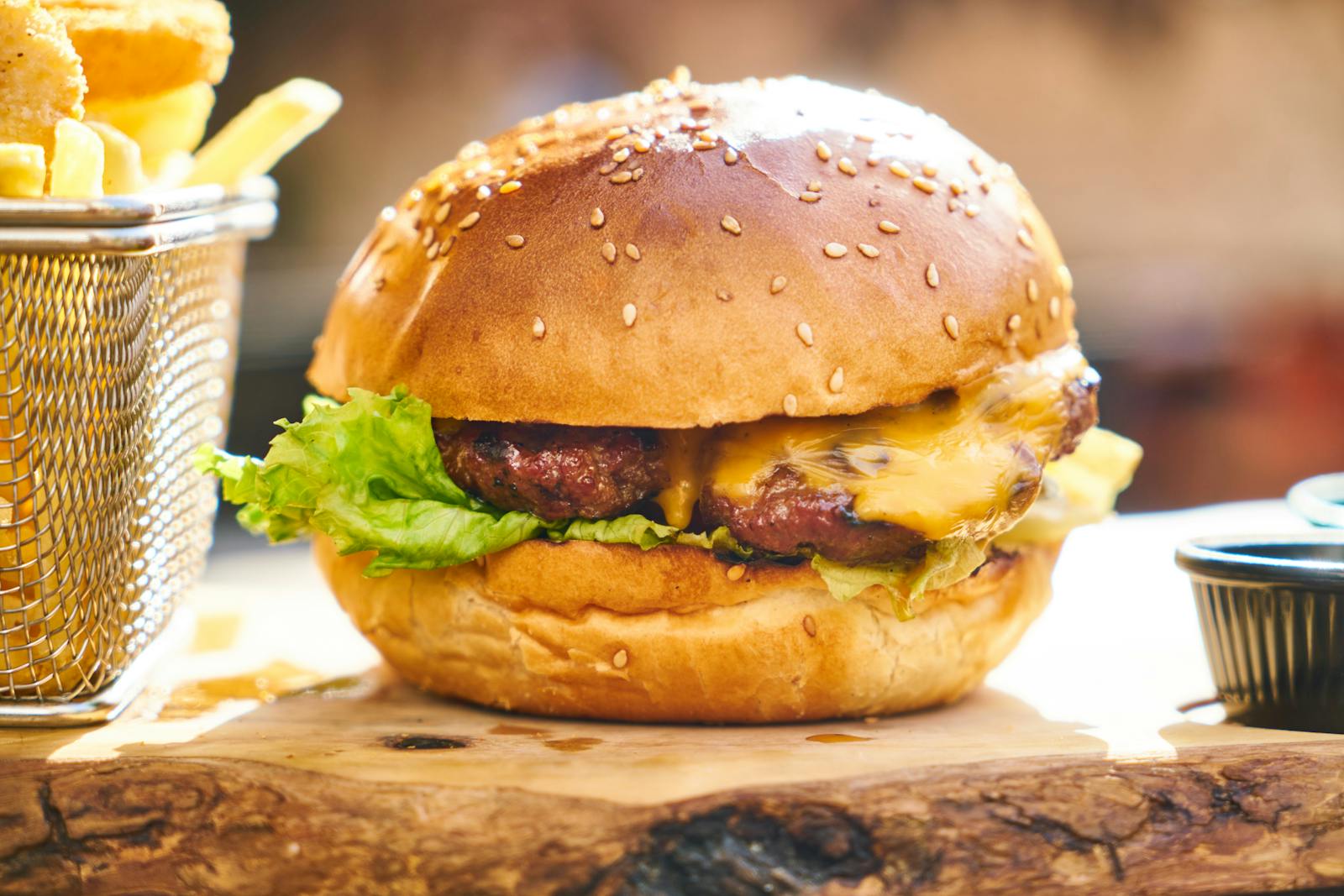 Juicy cheeseburger with crispy fries served on a wooden board, perfect fast food delight.