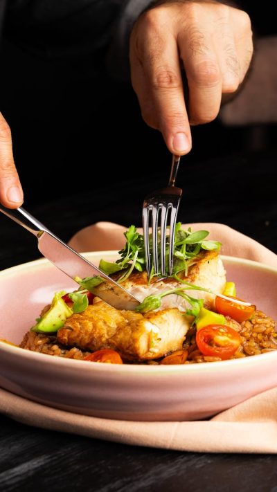 Close-up of a vibrant chicken meal with fresh herbs and vegetables on a pink plate.