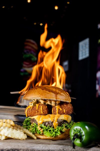 Delicious cheeseburger with jalapeño and fries, grilled to perfection with flames.