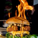 Delicious gourmet burger with jalapeño and fiery backdrop, showcasing spicy flavors and grilling perfection.