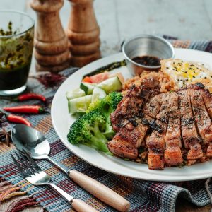 Delicious grilled pork with broccoli, cucumber, and egg served on rice for a tasty meal.