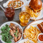 Top view of various casual dining meals including burger, fries, and drinks.