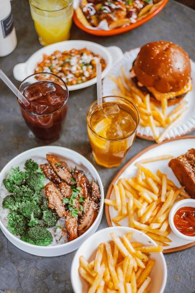 Top view of various casual dining meals including burger, fries, and drinks.