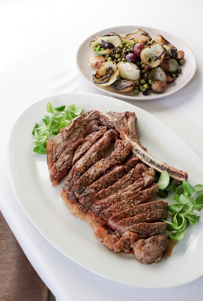 Juicy sliced ribeye steak served with a side of grilled vegetables for a delicious gourmet meal.