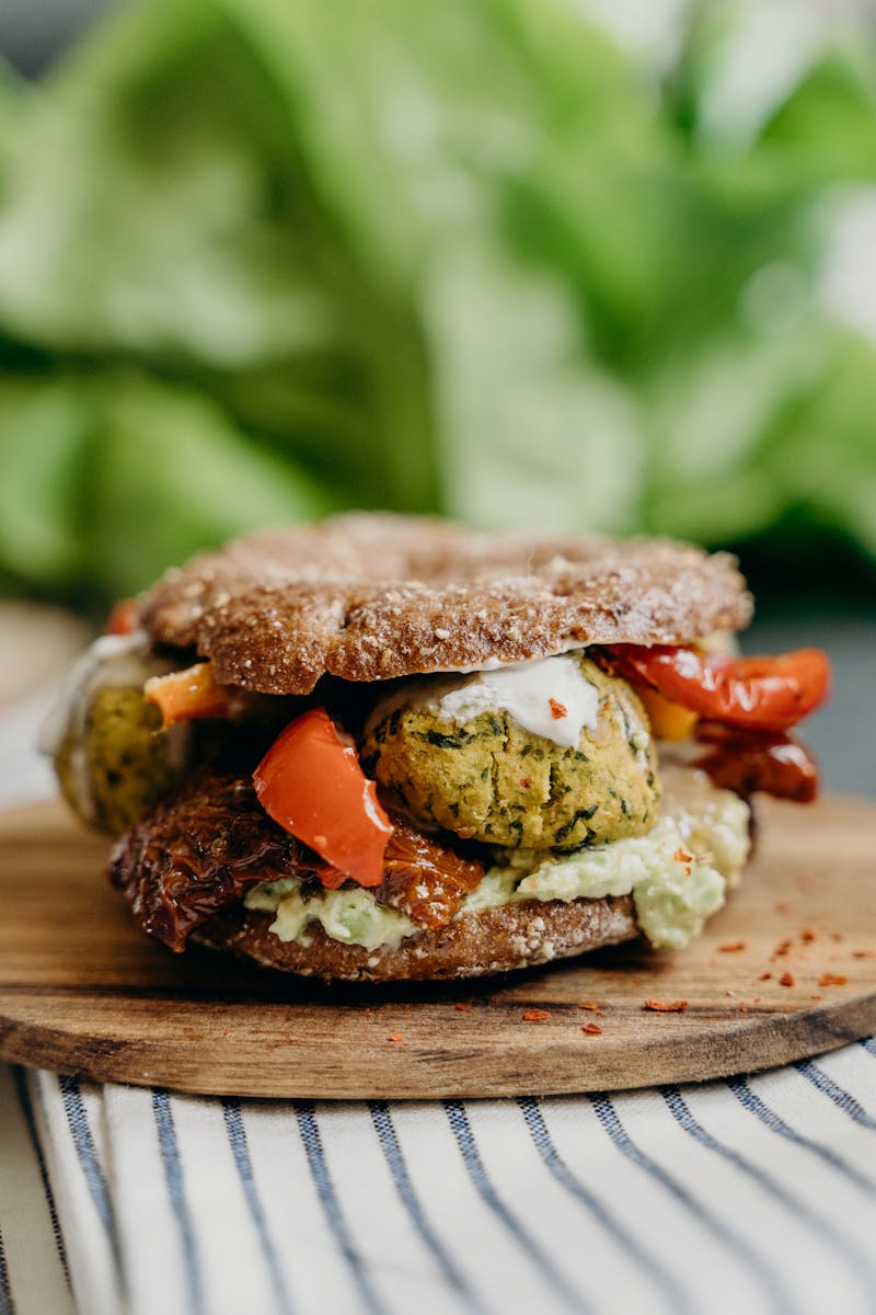 Close-up of a mouthwatering falafel sandwich with fresh vegetables and spices on rye bread.