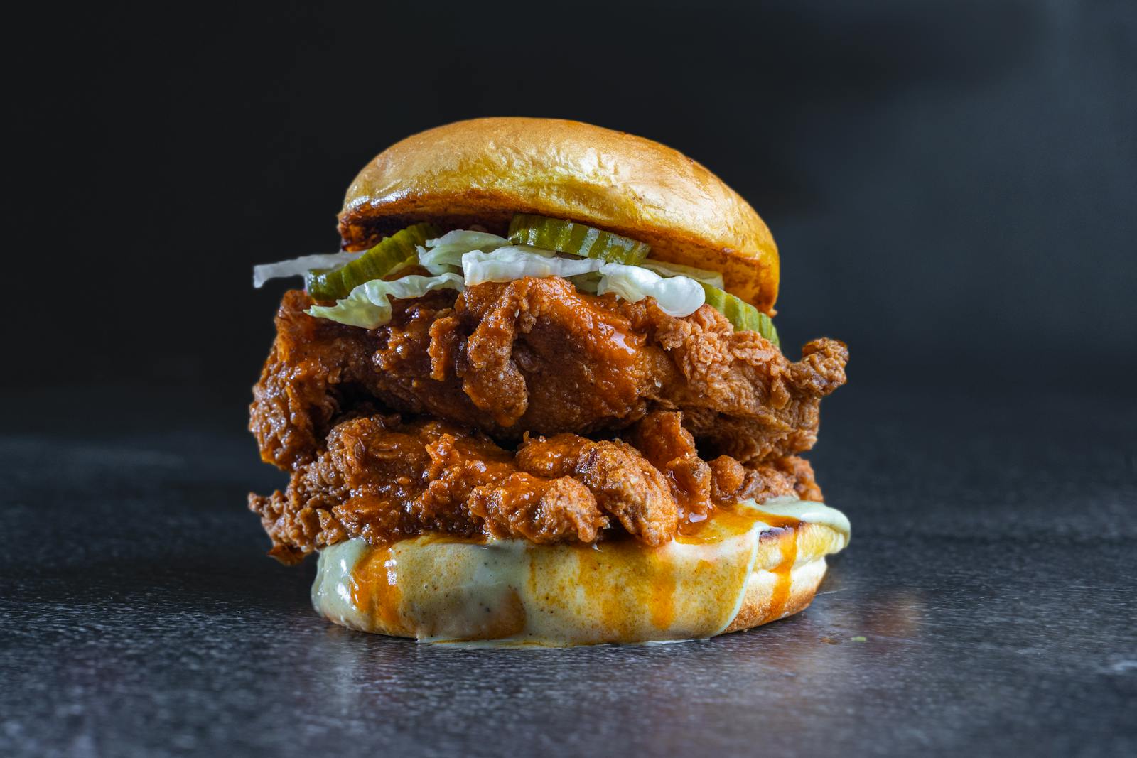 Delicious fried chicken burger topped with pickles and creamy cheese sauce.