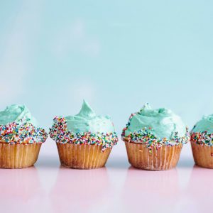 six teal icing cupcakes with sprinkles