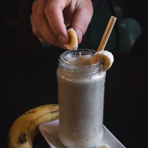 person holding slice of banana on fruit shake har