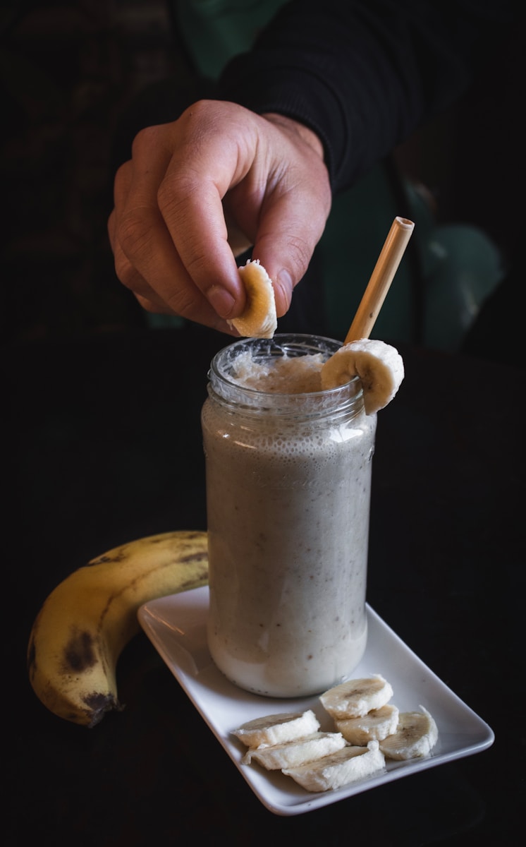 person holding slice of banana on fruit shake har