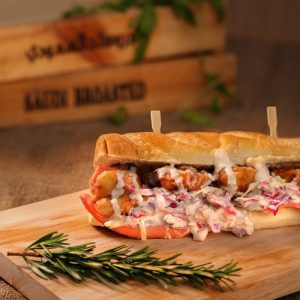 Delicious crispy chicken sandwich with creamy coleslaw on a wooden board, garnished with rosemary.