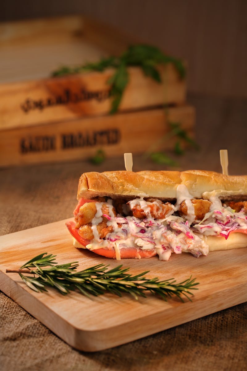 Delicious crispy chicken sandwich with creamy coleslaw on a wooden board, garnished with rosemary.