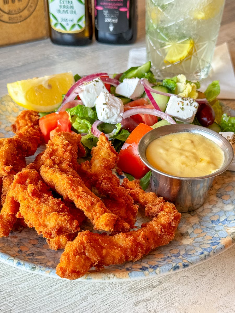 Golden fried chicken strips served with a Greek salad and creamy dip.