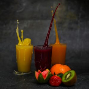 three yellow orange and green juice in clear drinking glasses